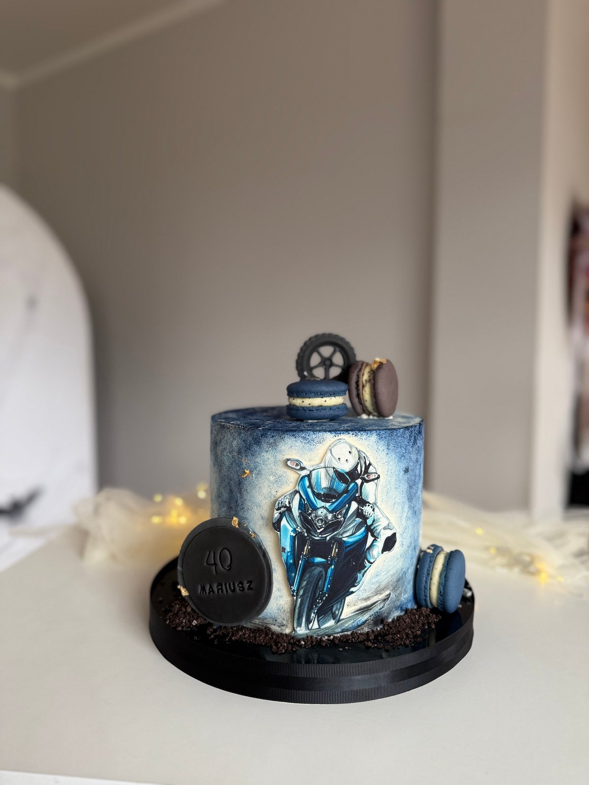 Motorcycle-themed birthday cake with blue airbrushed design, motorcycle wheel toppers, and number 40 decoration on black base